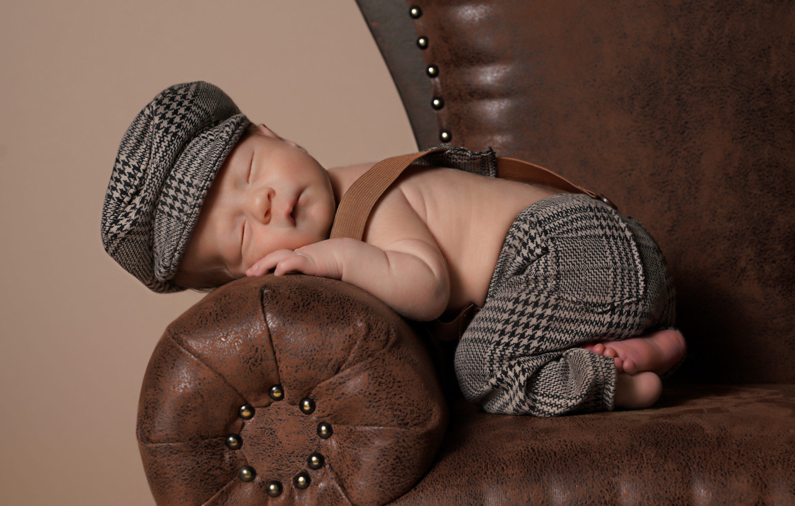 Newborn portrait sleeping on a couch arm.