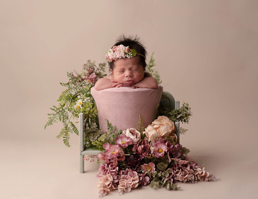 Newborn portrait of baby in a floral arrangement, Orlando FL.