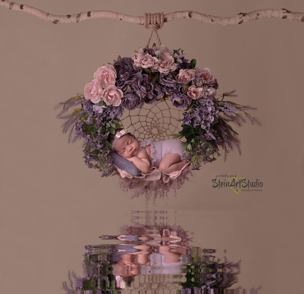Newborn portrait of baby in a swing adorned with various purple flowers