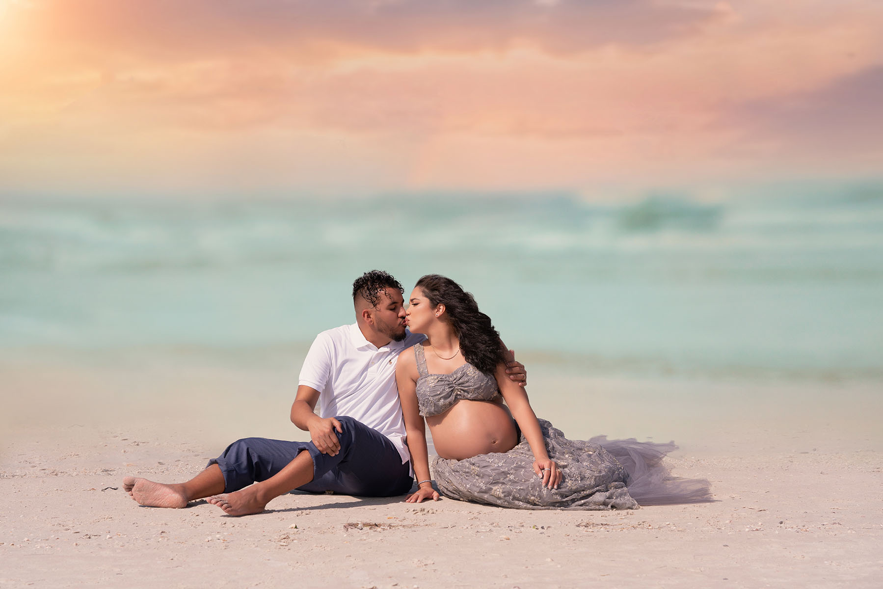 Maternity couples portrait of couple posed on a beach at sunset