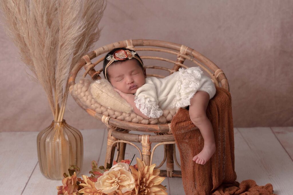 Newborn portrait of a baby in a papasan chair with bohemian styling