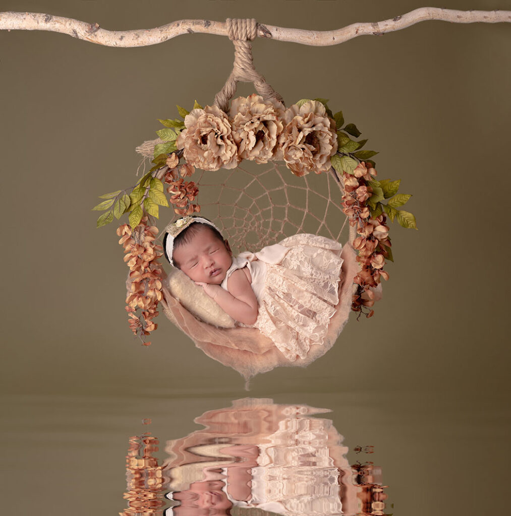 Newborn portrait of baby girl in a circular swing adorned with flowers
