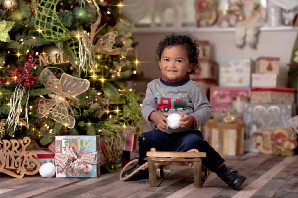 Christmas portrait of young boy sitting beside a christmas tree