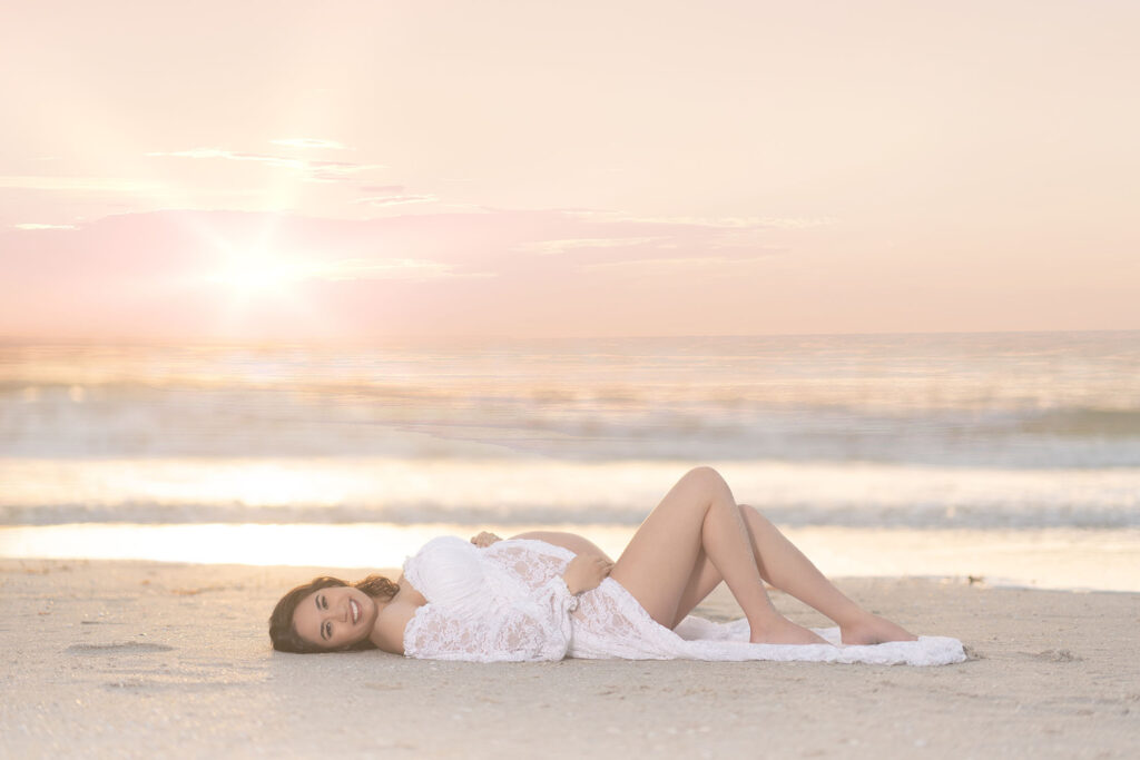 Maternity portrait of a woman laying on the beach at sunset