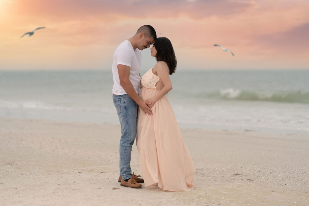 Couples maternity portrait of couple posed on a beach at sunset