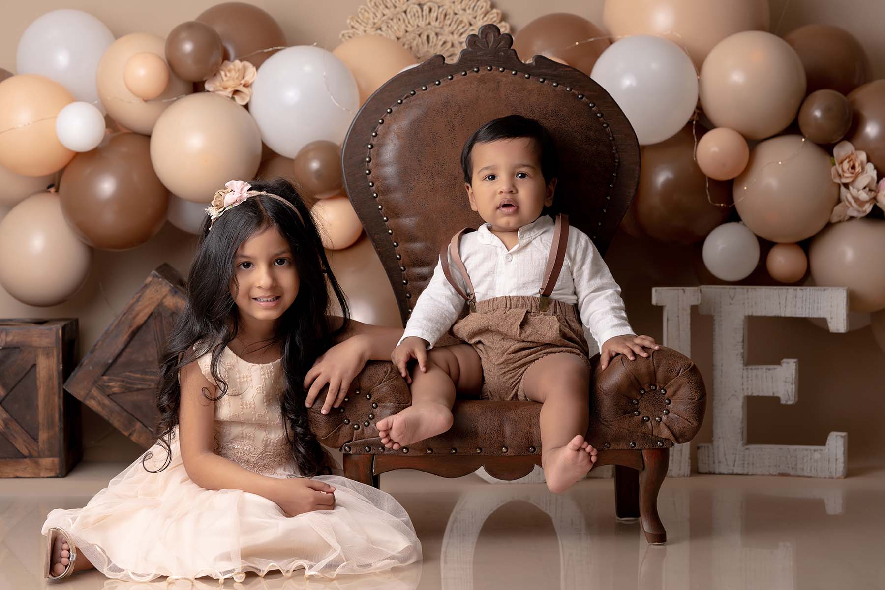 Portrait of siblings in a neutral and brown set with balloons
