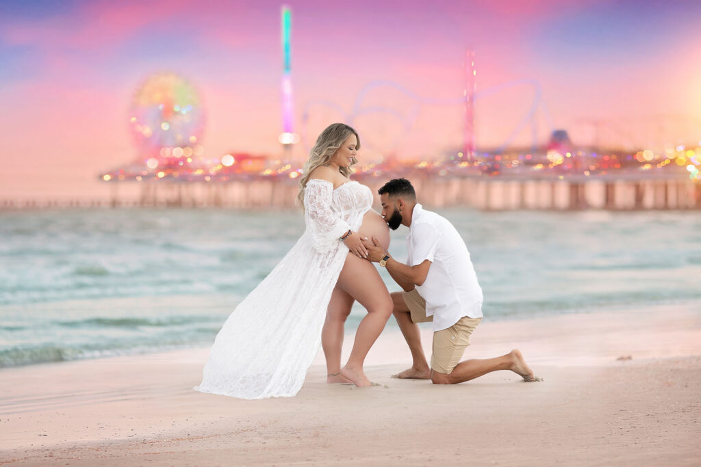 Couples maternity portrait of a couple posed on a beach with the sunset in the background