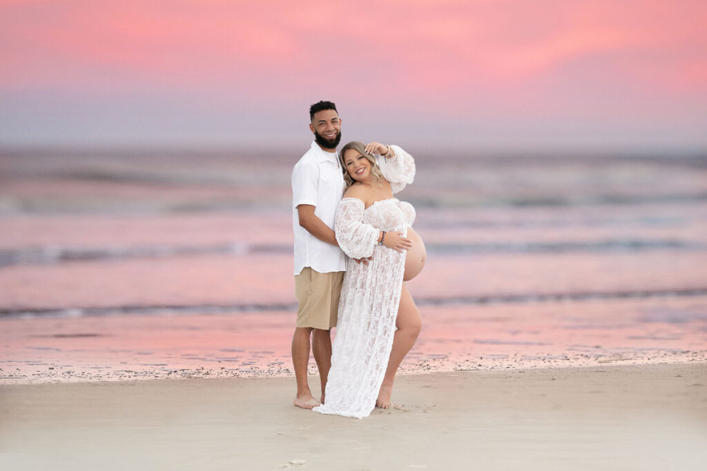 Couples maternity portrait of a couple at the beach with the sunset in the background