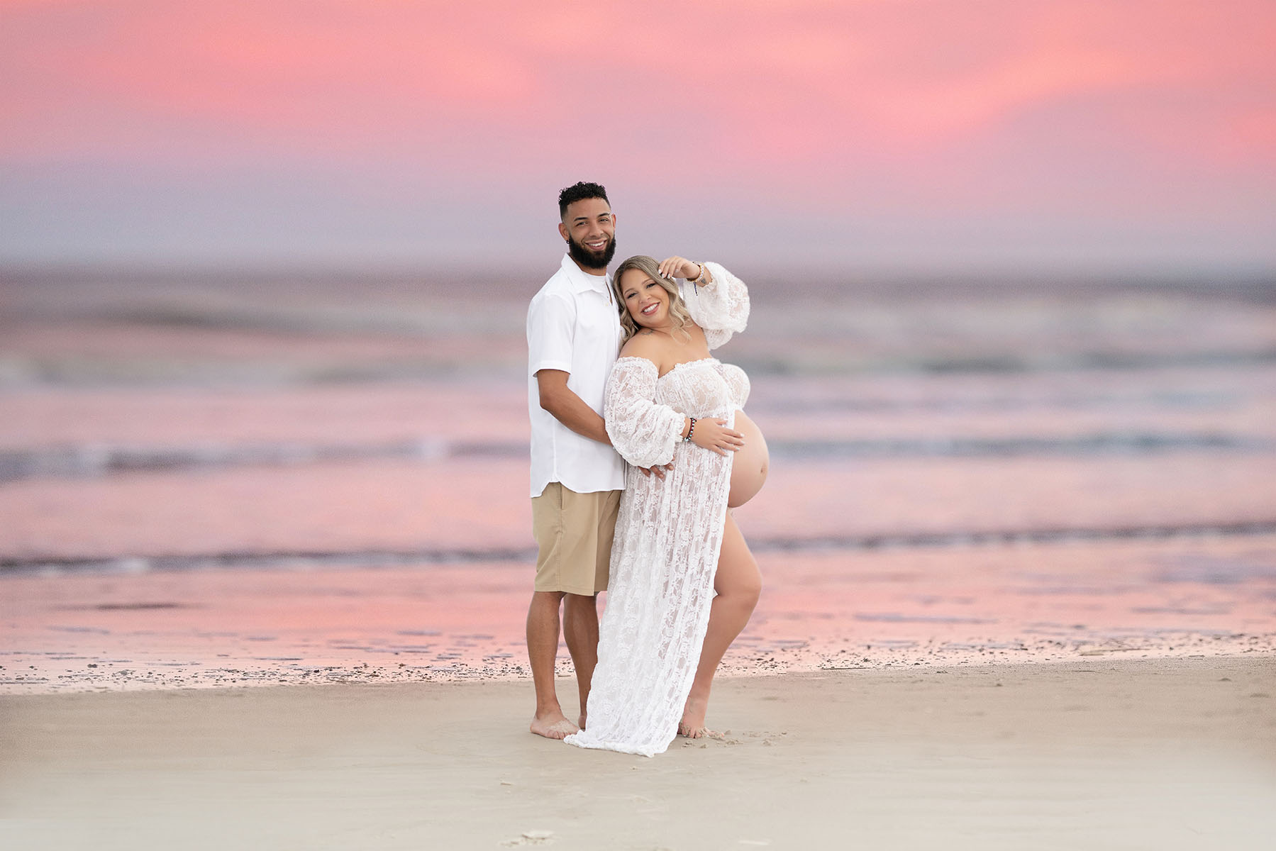 Couples maternity portrait of a couple at the beach with the sunset in the background