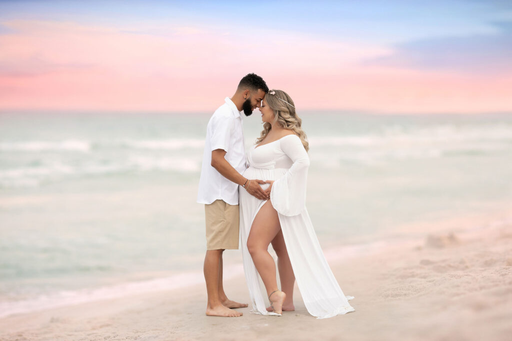 Couples maternity portrait on the beach with the sunset in the background