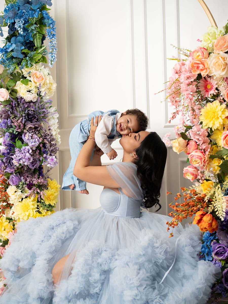 Portrait of mother and baby boy in a set with a white background adorned by flowers